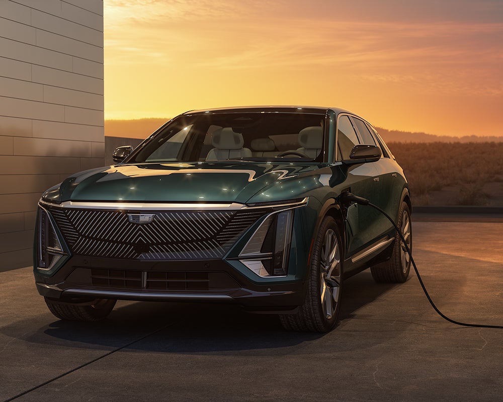 A Cadillac Lyriq Electric Vehicle Parked In Front of a Home at Dusk